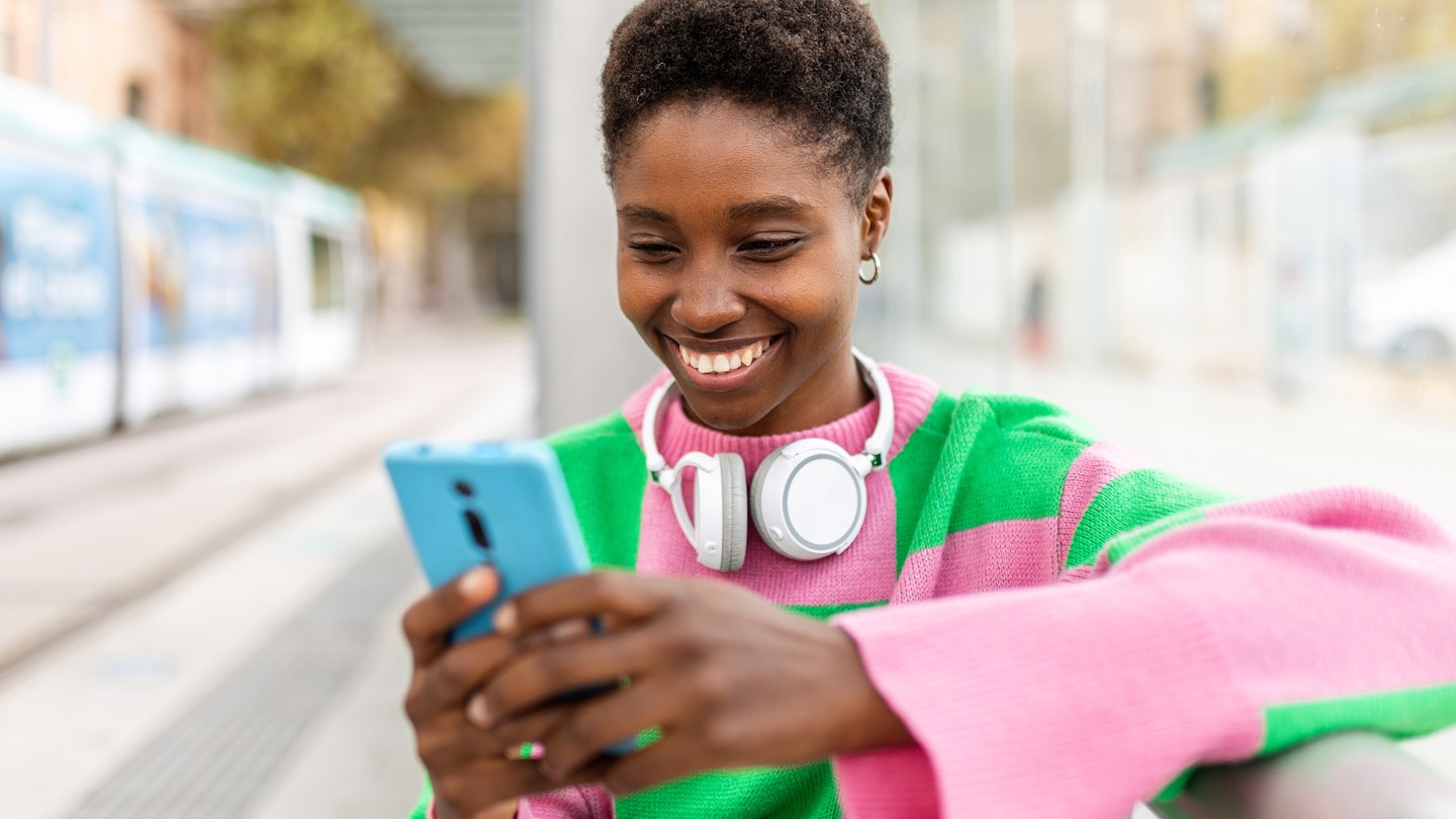 Happy young trendy african woman using mobile phone while waiting for the train at outdoors station
1439709091